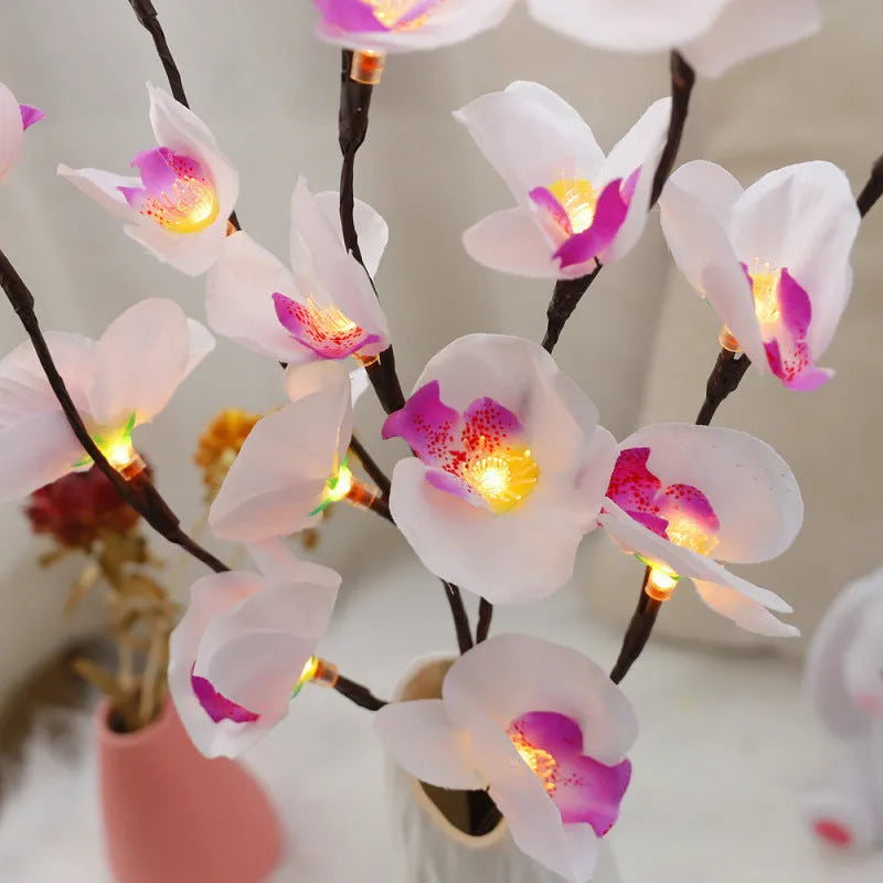 Pink phalaenopsis branch LED decorative light with fabric stem and plastic housing on wooden table