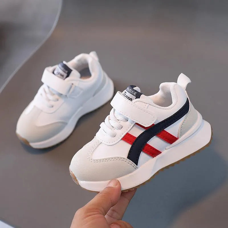 Children's solid colour sneaker with Velcro strap fastening, shown in beige with a rubber sole.