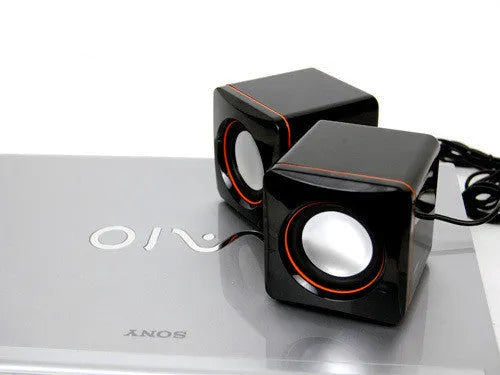 Black square USB-powered 2.0 computer speaker on desk with single cable connection
