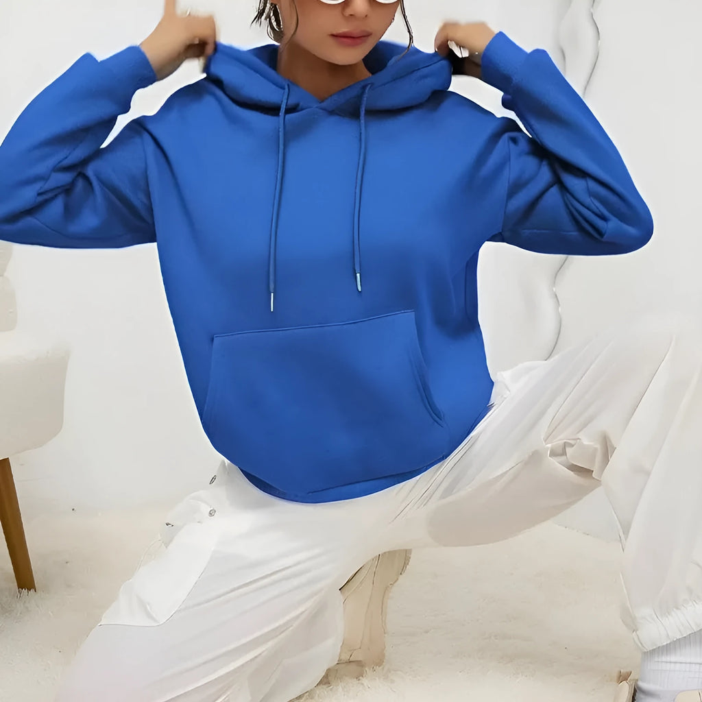 A woman wearing a loose grey drawstring hooded sweatshirt with a front pocket, showing the relaxed fit.