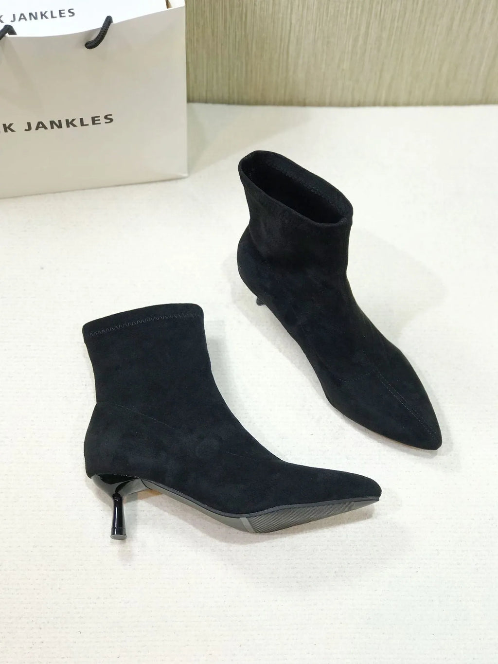 Women's black pointed toe ankle boots with a stiletto heel on a white background.