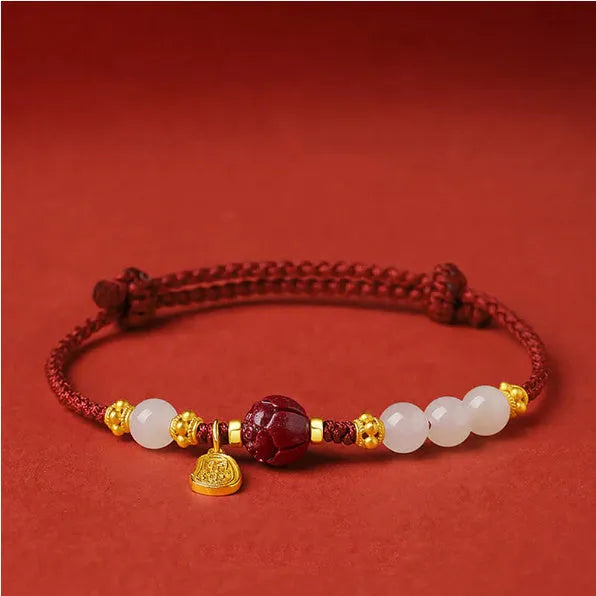 Women's adjustable silver bracelet with Hetian jade and red cinnabar rope decoration on a light background