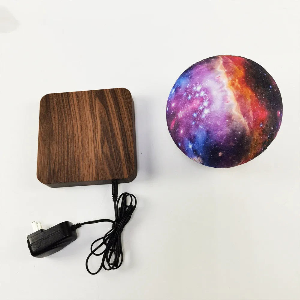 Square walnut coloured base with a levitating, glowing galaxy-patterned moon lamp above it