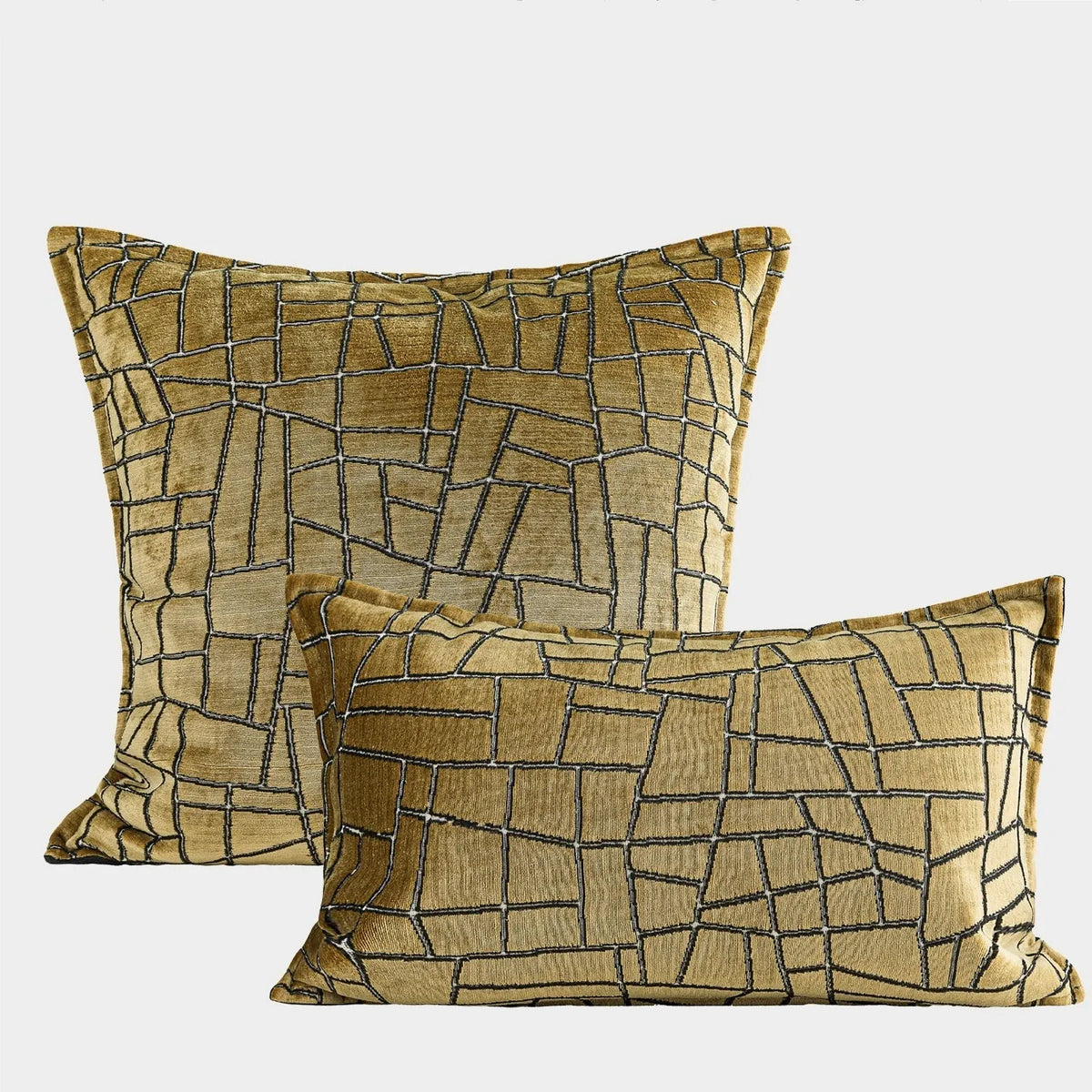 Gold geometric abstract pattern on a velvet square decorative cushion on a grey sofa.