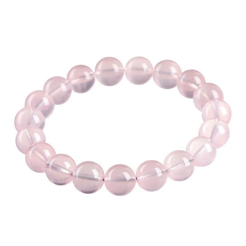 Close-up of a women's bracelet with polished round pink crystal beads on a single strand, showing smooth surface and sparkle.