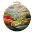 Embroidery DIY kit with cotton landscape fabric, bamboo frame, needles, and thread on wooden table