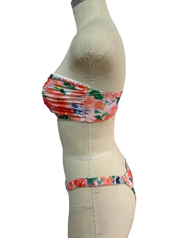 Women's floral print tube top bikini set with lace trim on a blue background.