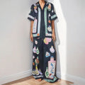 Black women's cardigan and pants set with cartoon animation pattern, laid flat.