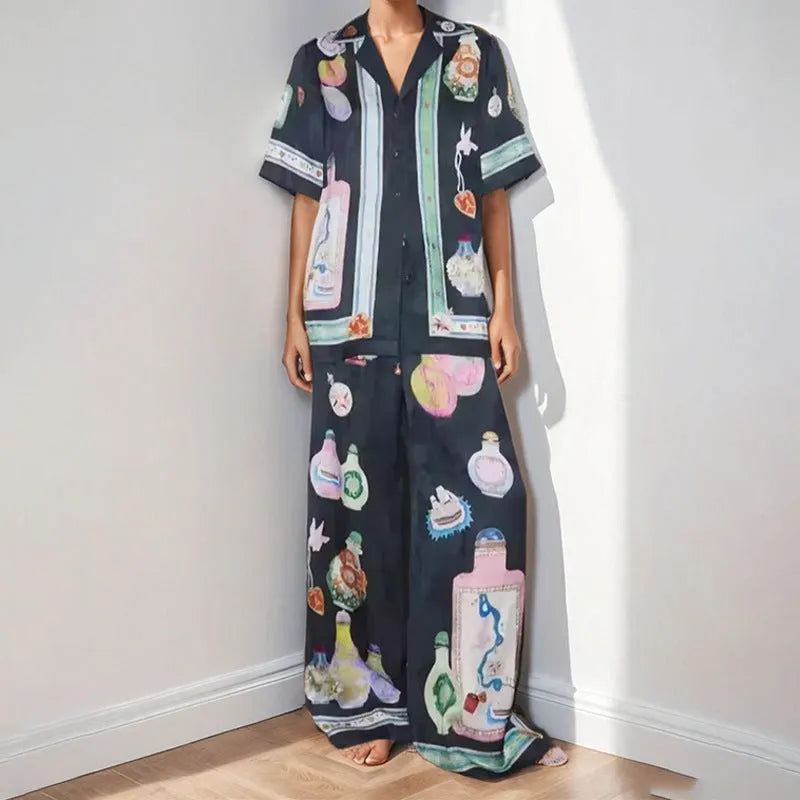 Black women's cardigan and pants set with cartoon animation pattern, laid flat.