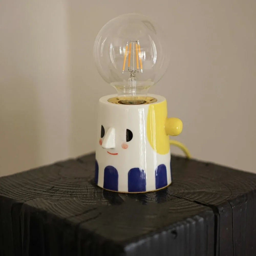 Handmade ceramic table lamp with white ball headlight design on wooden surface