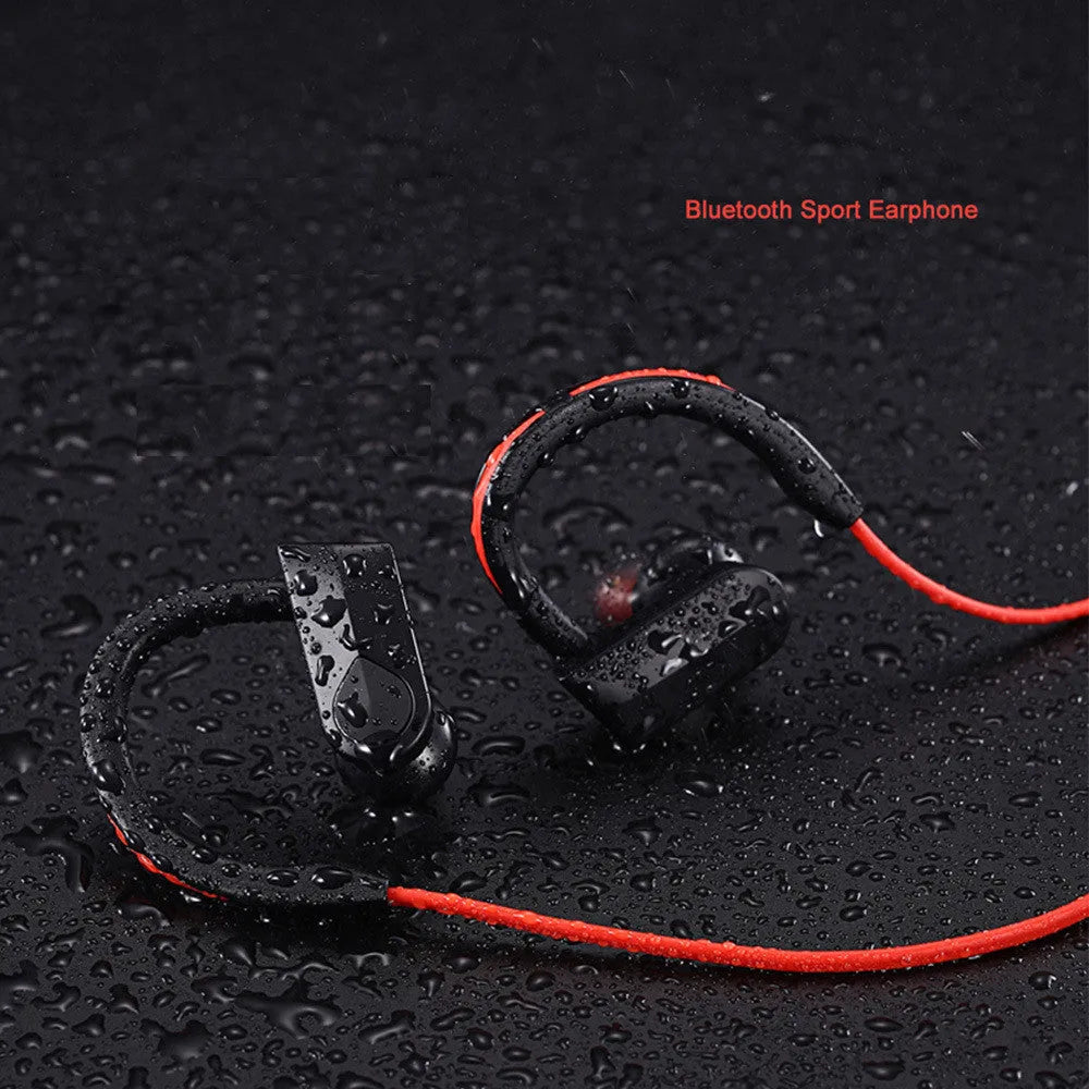 Black wireless neckband Bluetooth earphones with earbuds and a USB charging cable on a grey background.
