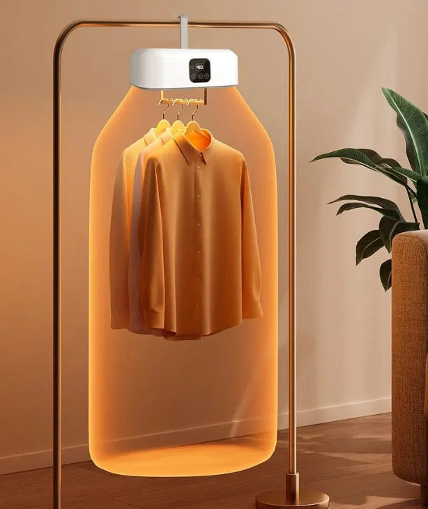 White cylindrical compact electric clothes dryer with remote control on a table.