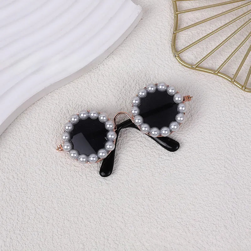 Pearl-rimmed round sunglasses for cats and dogs on a coloured background.