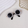 Pearl-rimmed round sunglasses for cats and dogs on a coloured background.