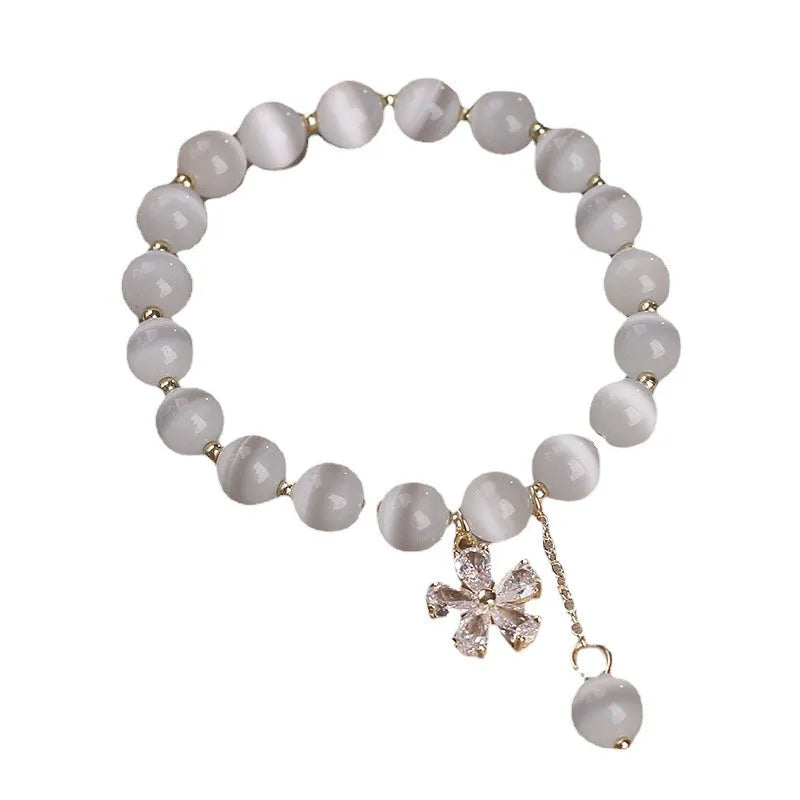 Women's white cat's eye crystal bracelet with flower tassel detailing and safety buckle pendant