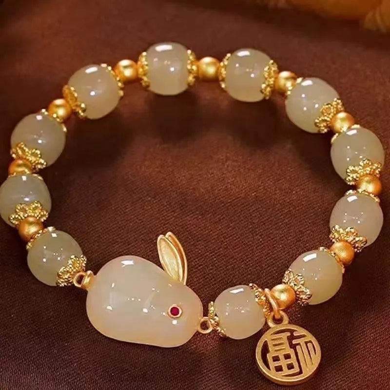 Close-up of a black women's bracelet with a green jade fu character charm and a metal hare pendant.