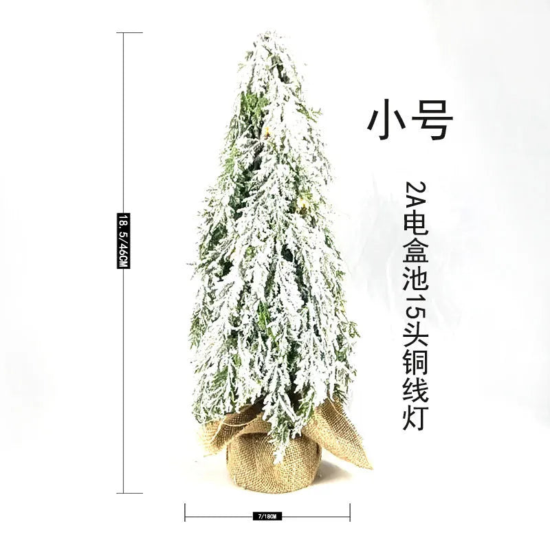 Small white artificial Christmas tree with built-in lights and snow sprayer decoration on desktop