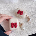 Beige and red TPU clamshell case with a bow pendant for AirPods 1, 2, 3 and Pro 3 models.