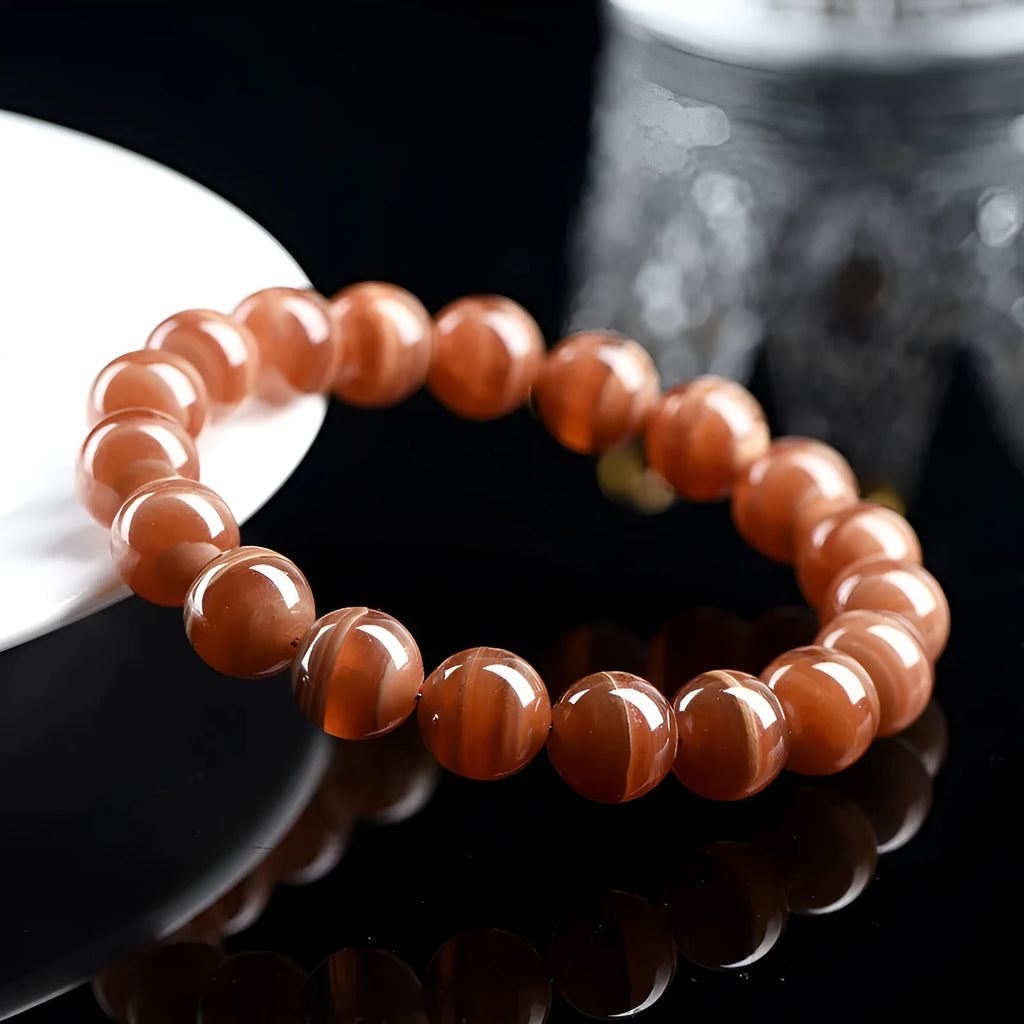 Natural Old Mine Rhodochrosite round bead bracelet with Ruyi design elements on a wrist.