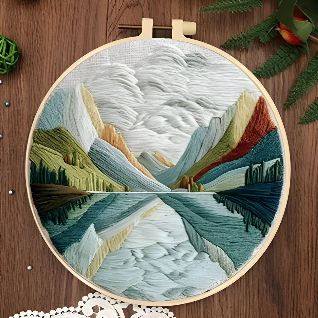 Embroidery DIY kit with cotton landscape fabric, bamboo frame, needles, and thread on wooden table
