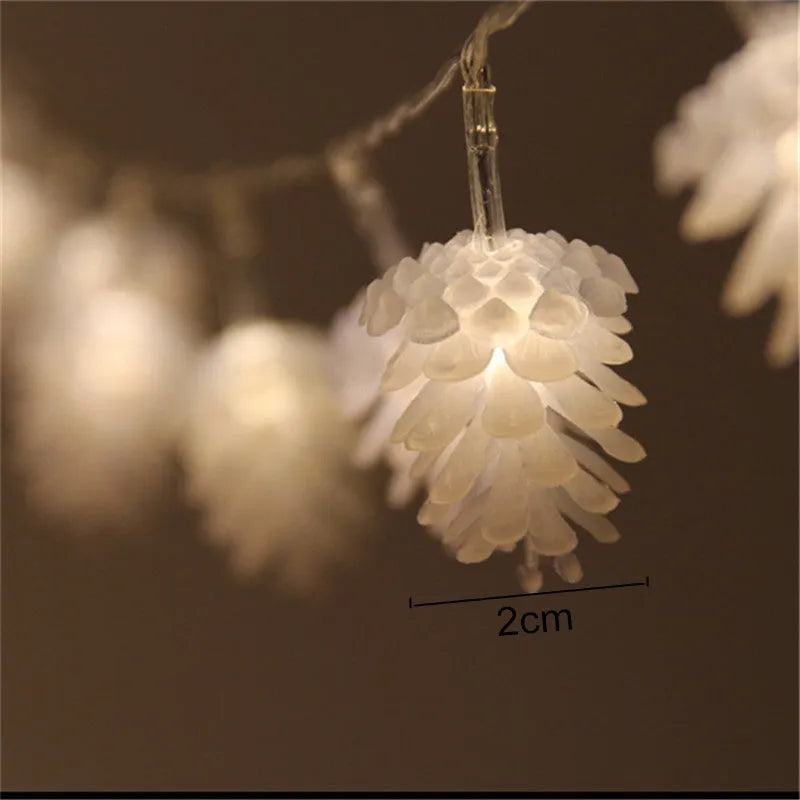 Warm white LED pine cone light string hanging decoratively, showing plastic shell details.