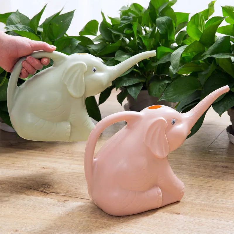 Pink baby elephant-shaped plastic watering can with a long spout on a wooden table.