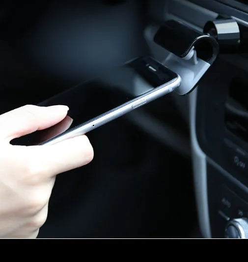 Black gravity car phone holder with 360-degree rotation on a car dashboard