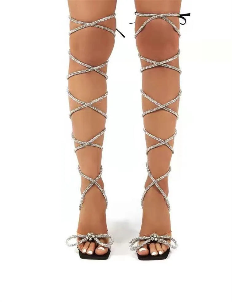 Plus size women's black strappy sandals with rhinestone Roman straps and a square toe.