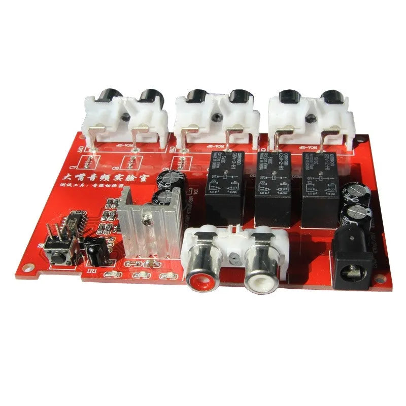 Silver aluminium audio source selector switch box with remote control on a dark surface.