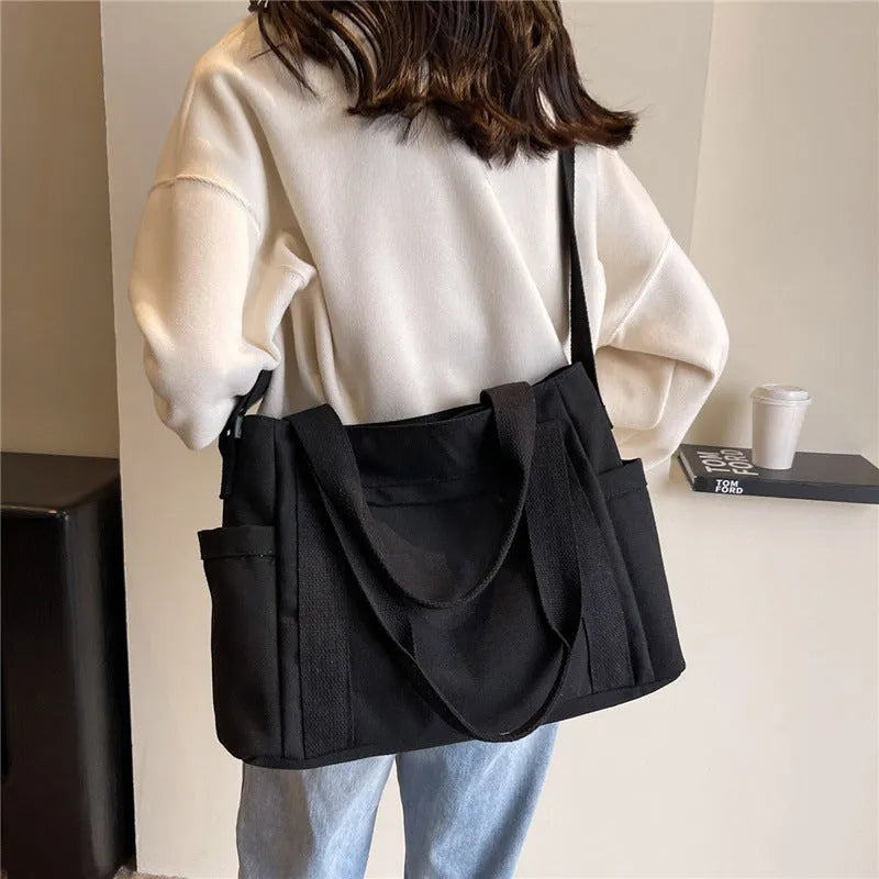 Women's solid colour canvas shoulder bag showing interior mobile phone compartment and exterior sandwich pocket