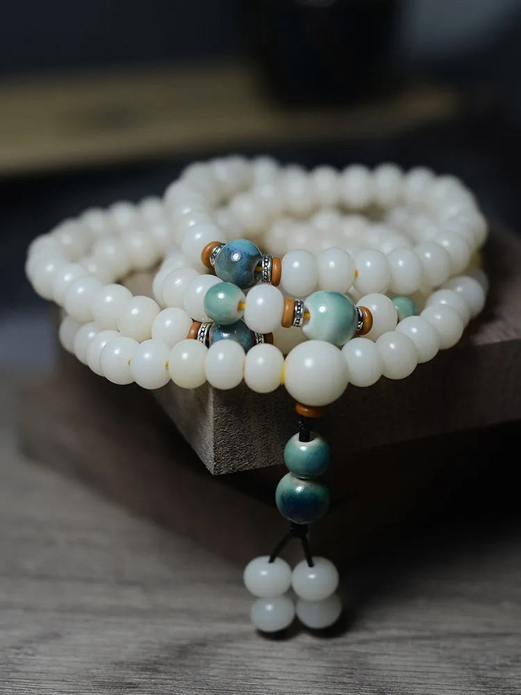 White jade bodhi root bracelet with 108 flat round beads in two sizes on a wrist.