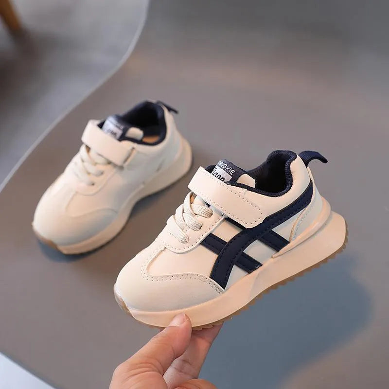 Children's solid colour sneaker with Velcro strap fastening, shown in beige with a rubber sole.