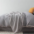 Small grey polyester nap blanket folded to show its size and texture.