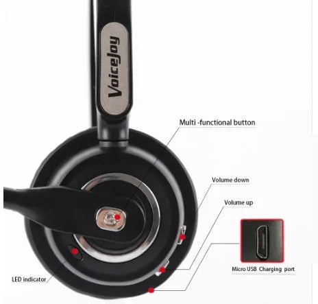 A black Bluetooth over-ear headset with a bendable microphone boom, shown on a desk next to a USB charging cable.