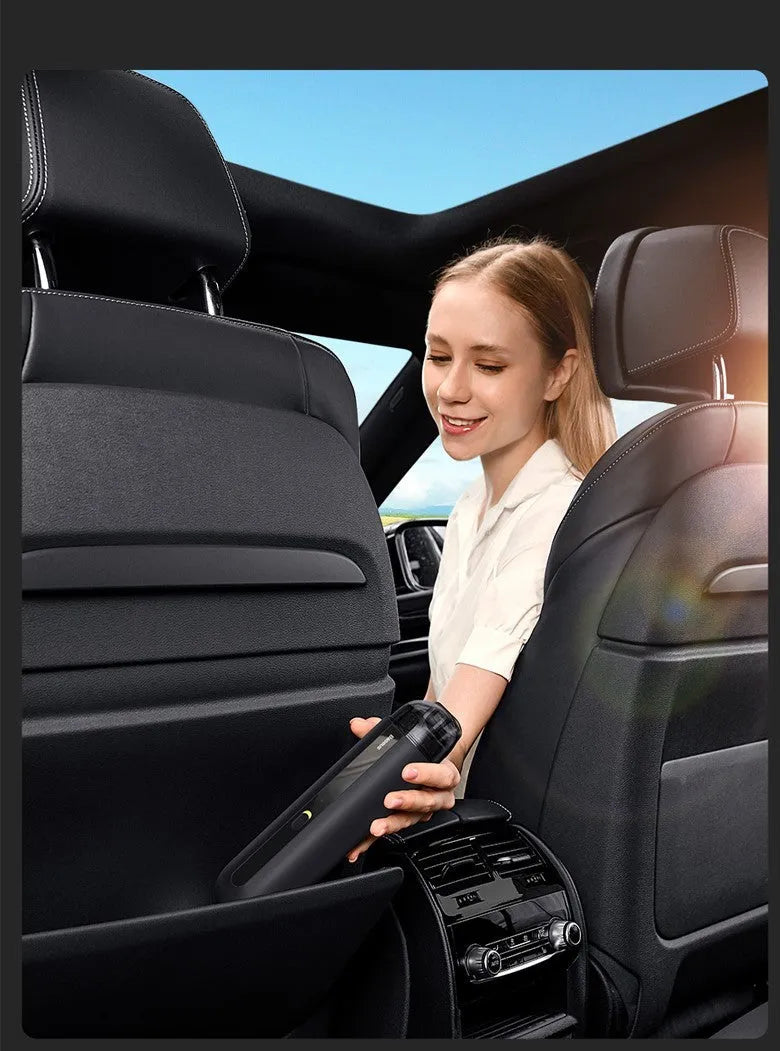 Black handheld wireless car vacuum cleaner with a blowing hose attachment on a desktop.