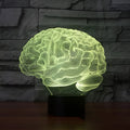 3D acrylic brain sculpture LED desk lamp with colourful illumination on a dark surface.