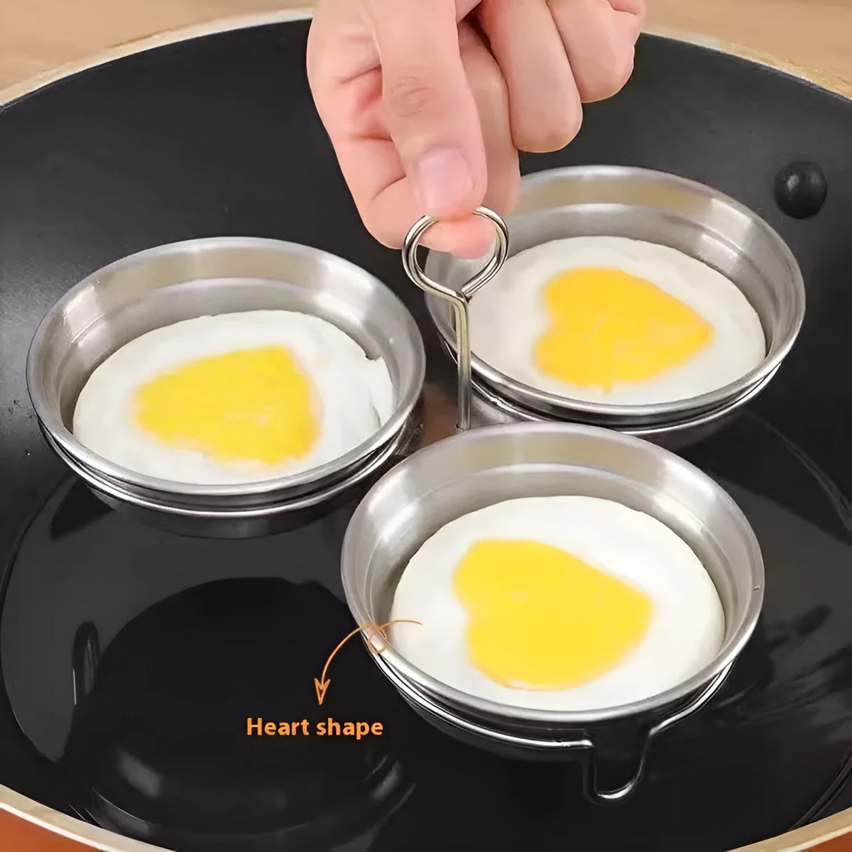 Stainless steel heart-shaped egg steamer for boiling eggs on kitchen counter.