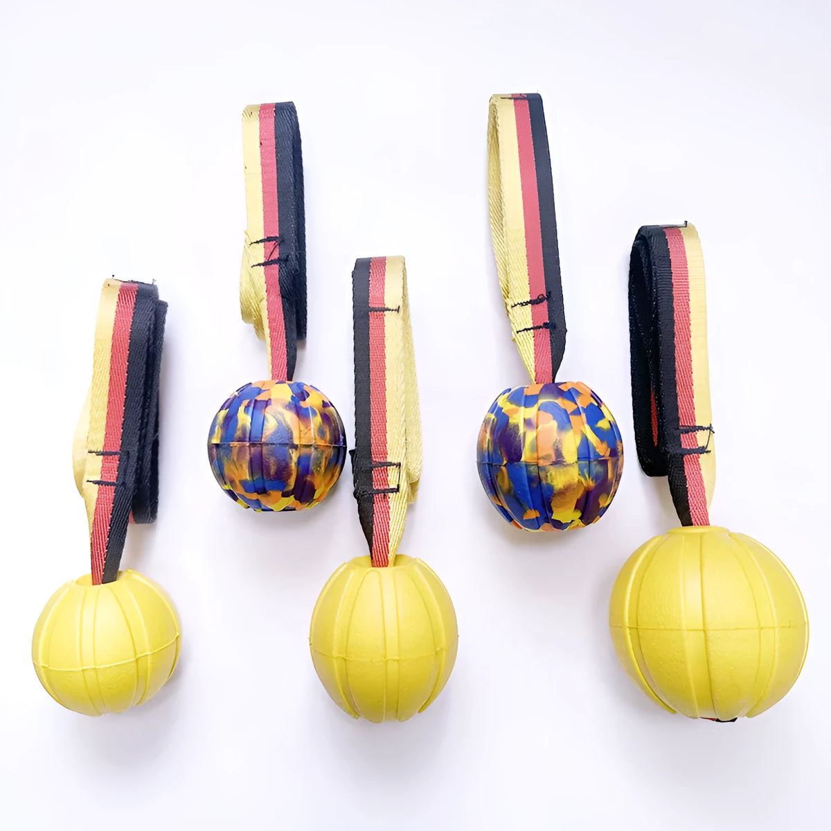 Yellow and camouflage coloured EVA floating dog chew balls in three different sizes on a blue background.