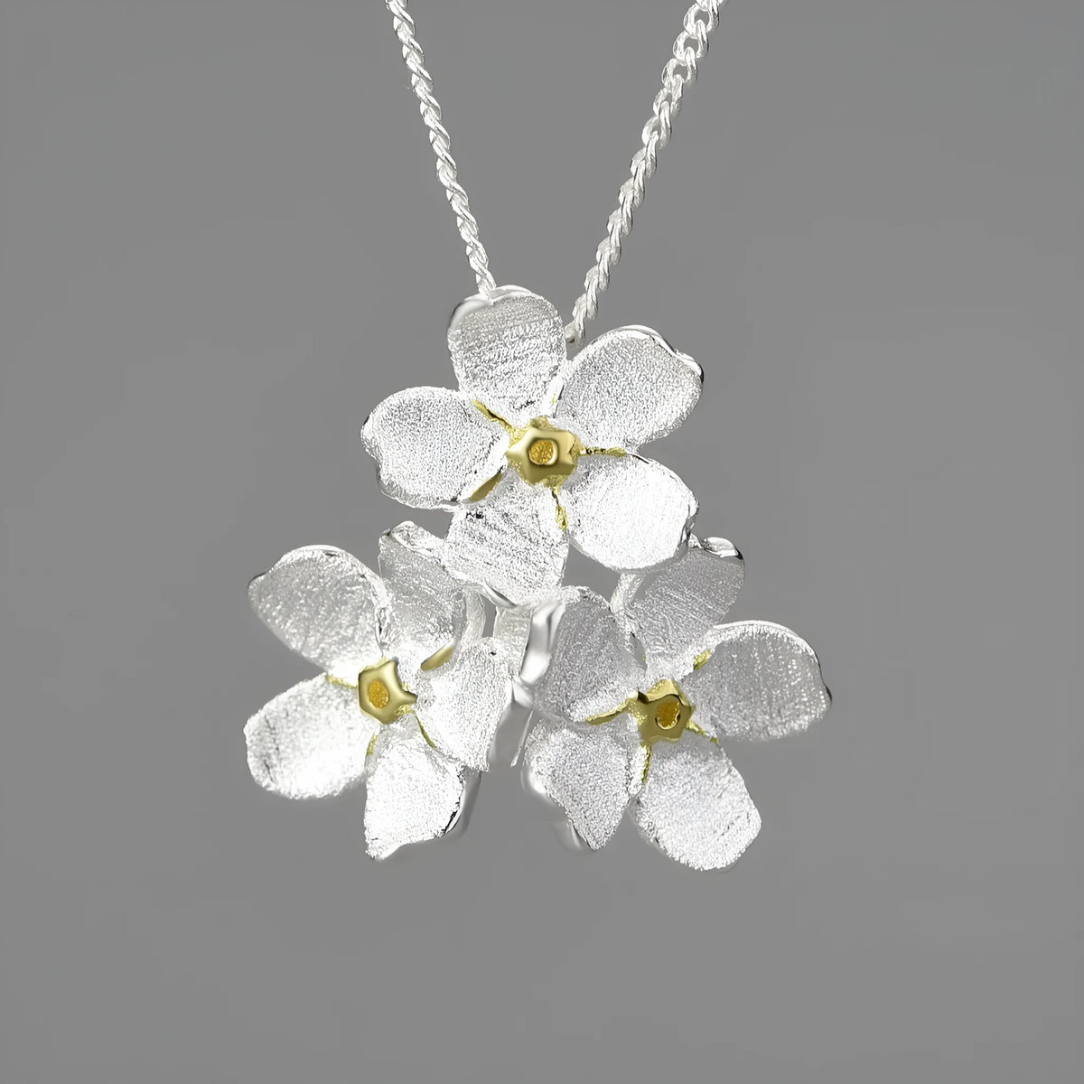 Sterling silver forget-me-not floral pendant in pastoral style, shown in gold and silver electroplated finishes.