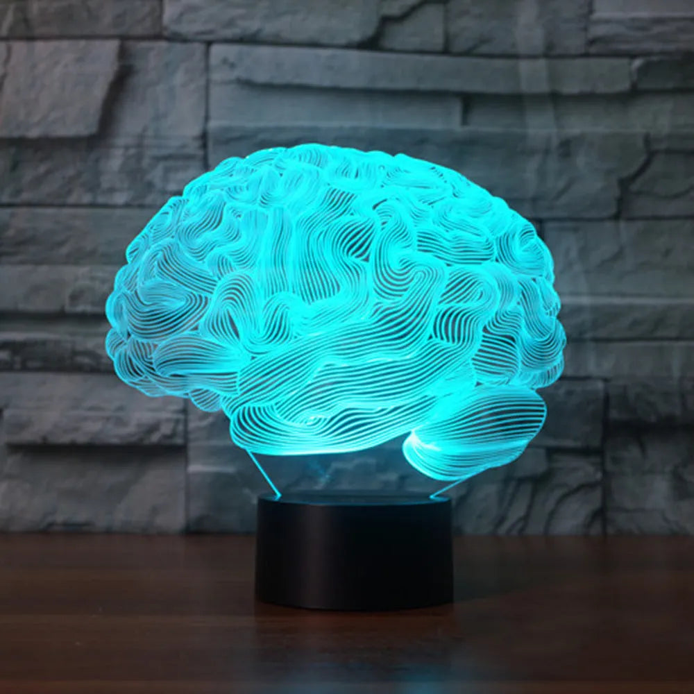 3D acrylic brain sculpture LED desk lamp with colourful illumination on a dark surface.