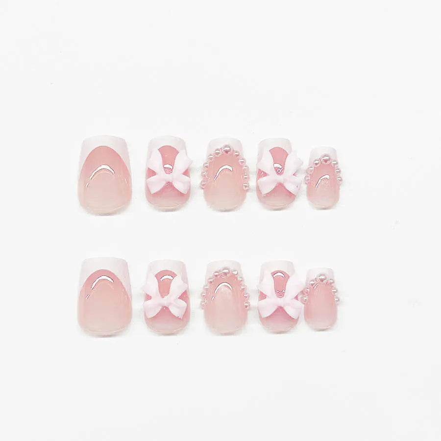 Short white French manicure false nails with decorative bow and tulip designs.