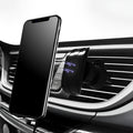 Black car phone holder clipped to car air vent with adjustable arms gripping a smartphone