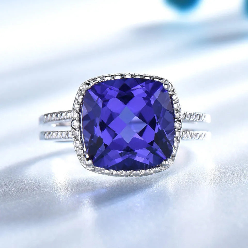 Blue tanzanite gemstone set in a sterling silver women's ring on a grey background.