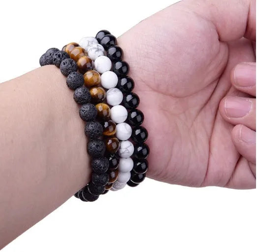 Geometric black onyx bracelet with 8mm beads on a black elastic cord, laid flat.