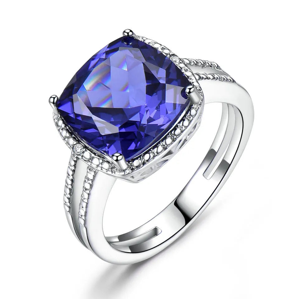 Blue tanzanite gemstone set in a sterling silver women's ring on a grey background.