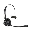 A black Bluetooth over-ear headset with a bendable microphone boom, shown on a desk next to a USB charging cable.