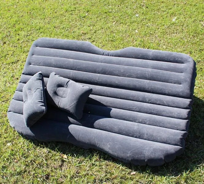 Universal inflatable car bed with flocked surface and pillows laid out in a car boot.