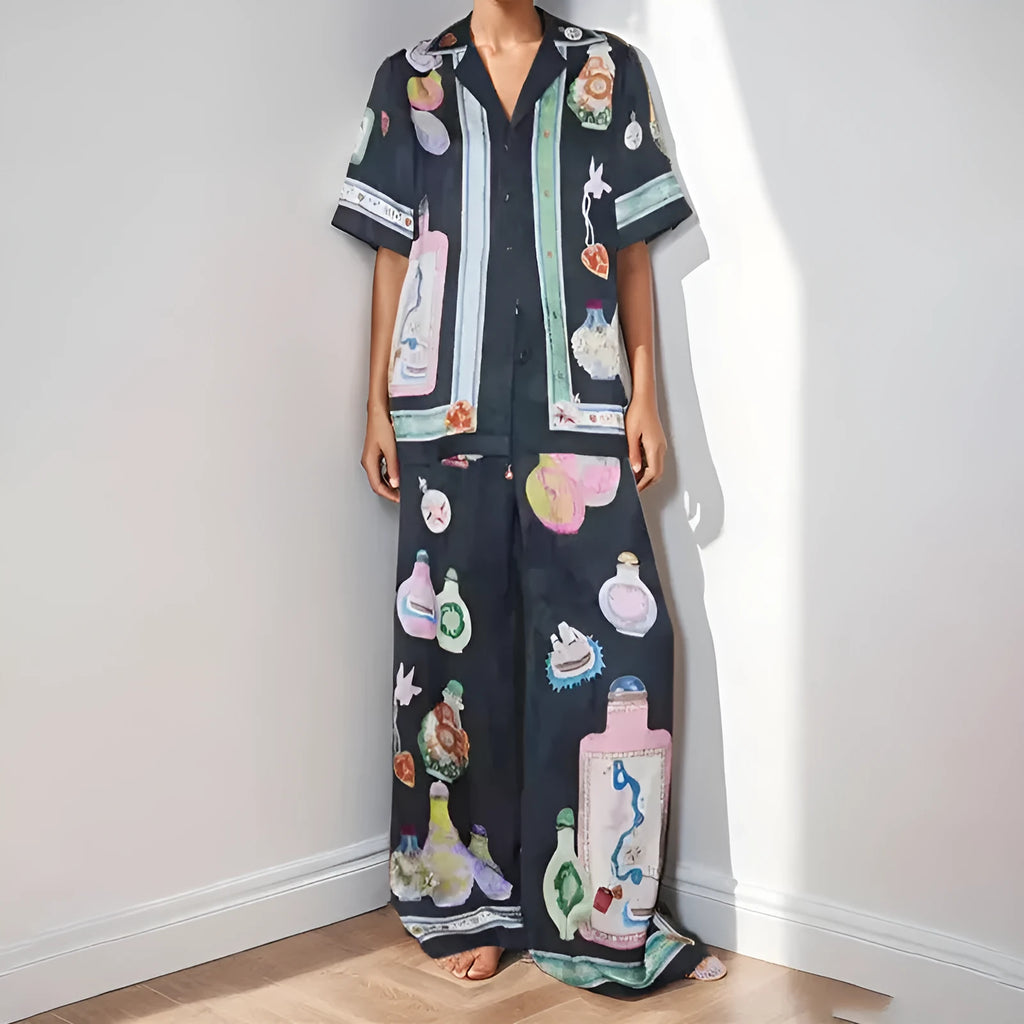 Black women's cardigan and pants set with cartoon animation pattern, laid flat.