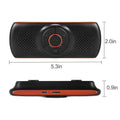 Orange plastic Bluetooth hands-free car speaker mounted on a sun visor for wireless smartphone calls and music.