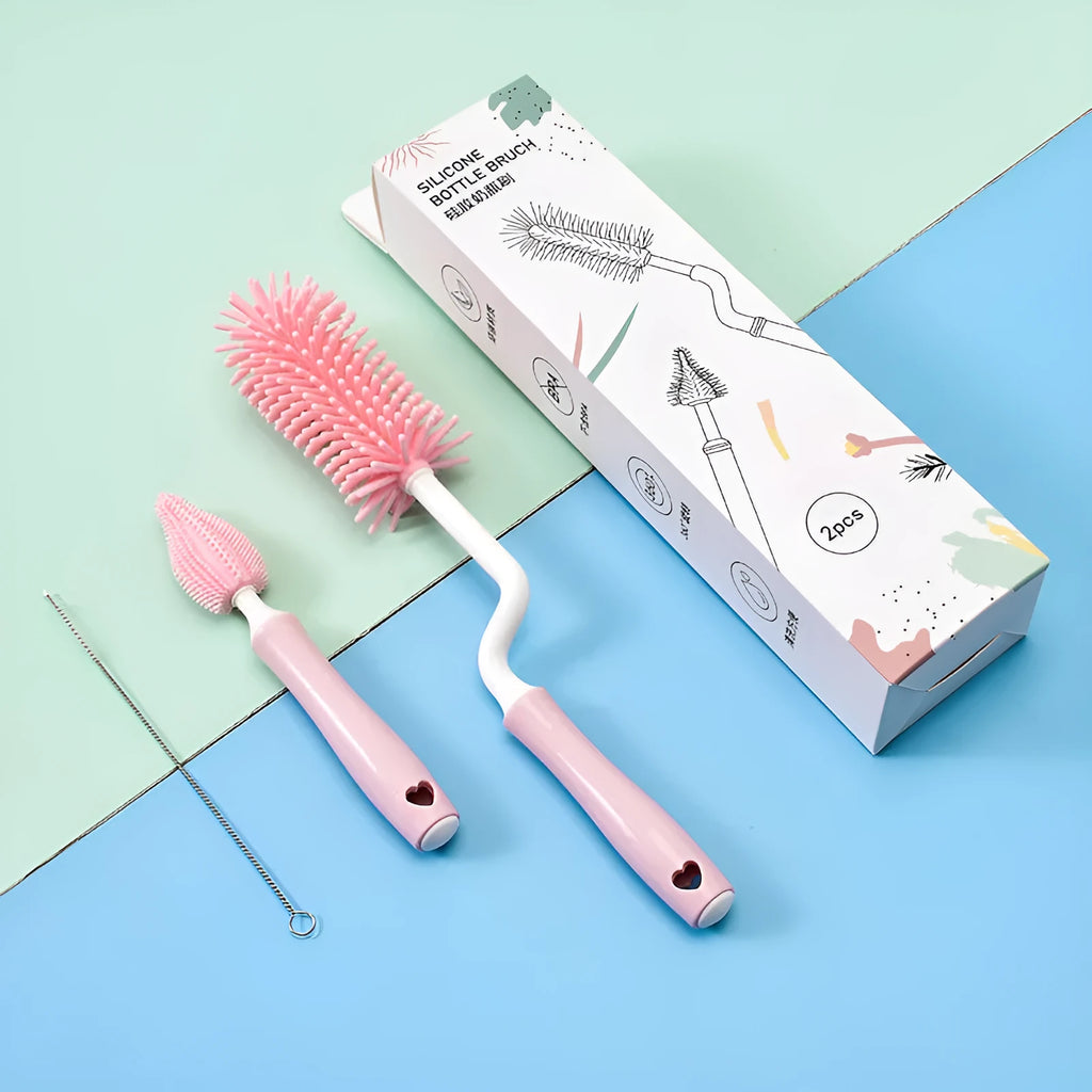 Three silicone baby bottle brushes on a counter, including a main brush and a narrow straw cleaning brush.